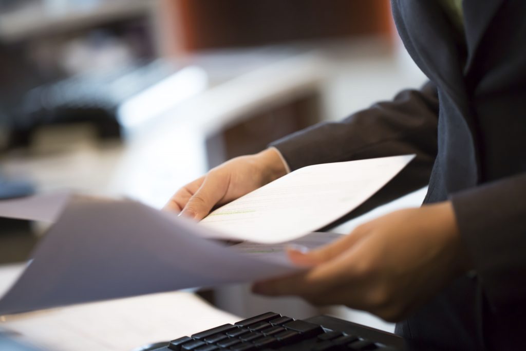 Woman is holding business documents in the office, close up, selective focus