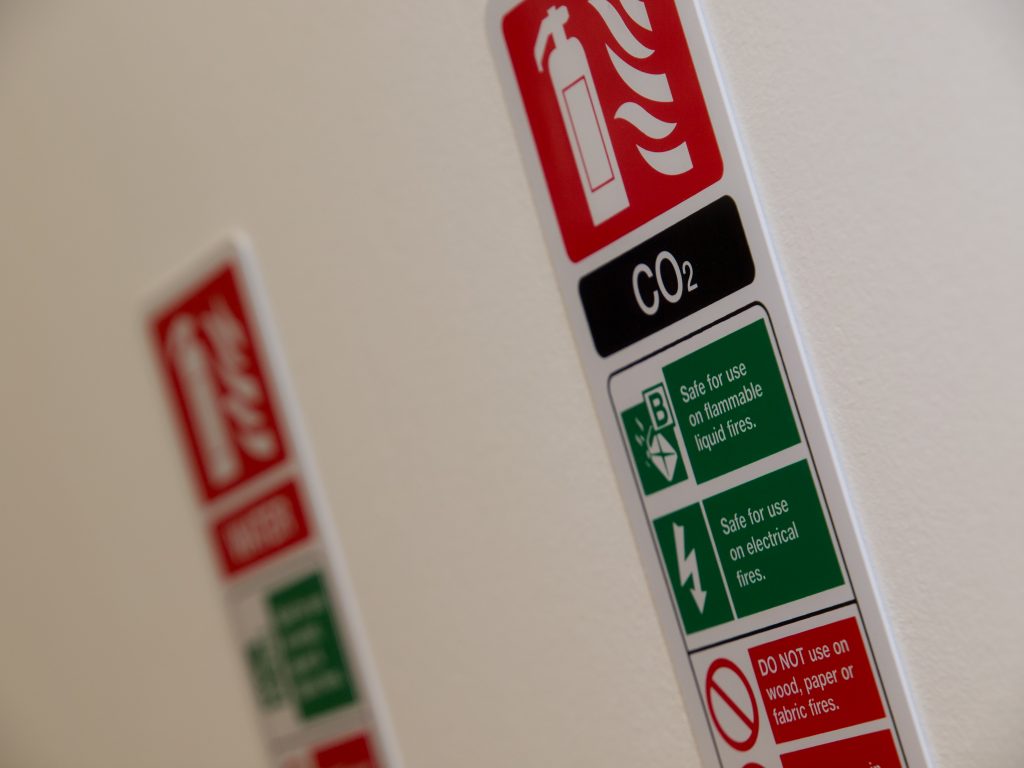 A set of different fire extinguisher instruction signs on a wall